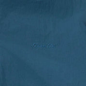 A close-up of a textured blue fabric with the words 'Sunrise Club' embroidered in a matching blue script in the center.