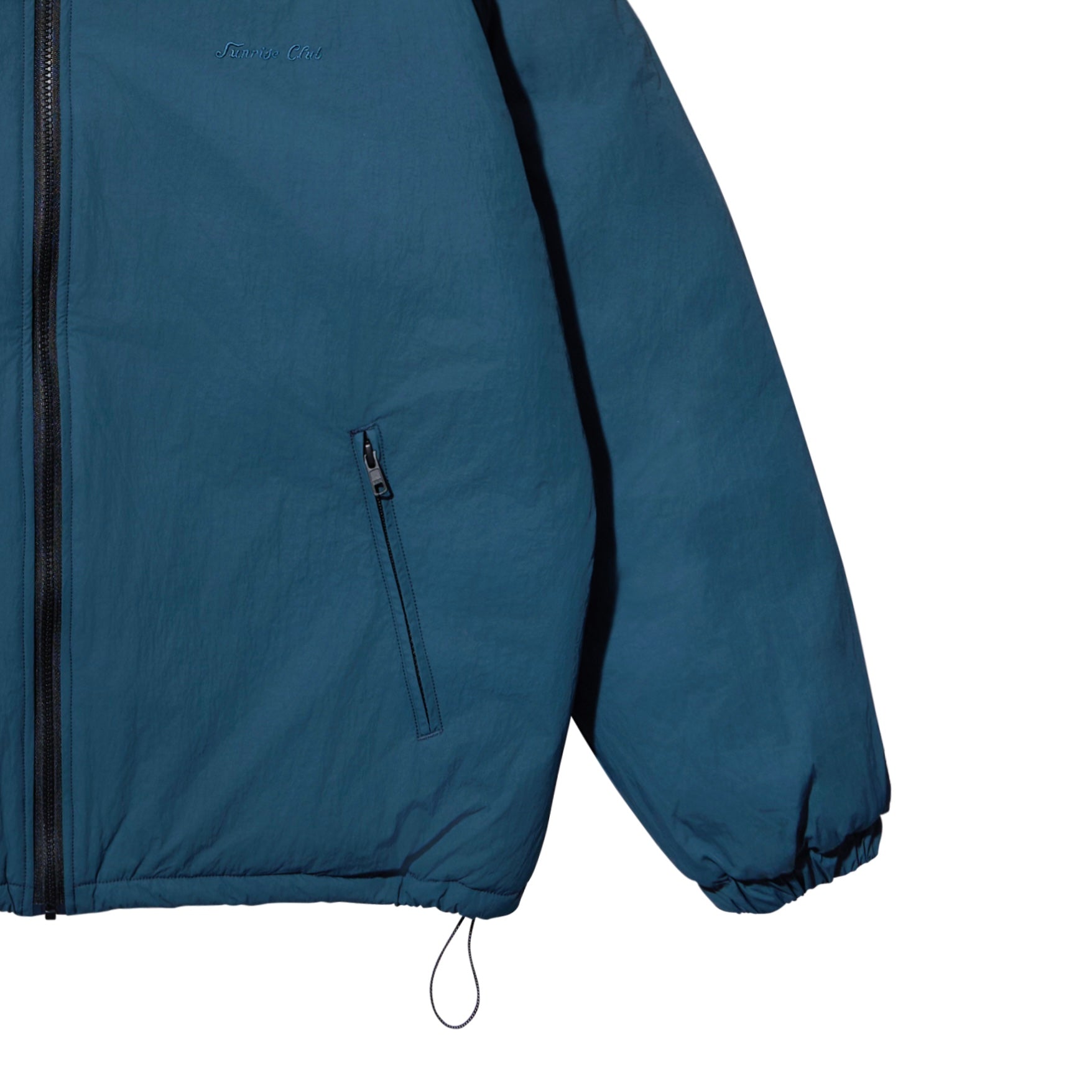 Close-up of a teal blue lightweight jacket with black zippers, elastic cuffs, and a drawcord hem, shown on a plain white background.