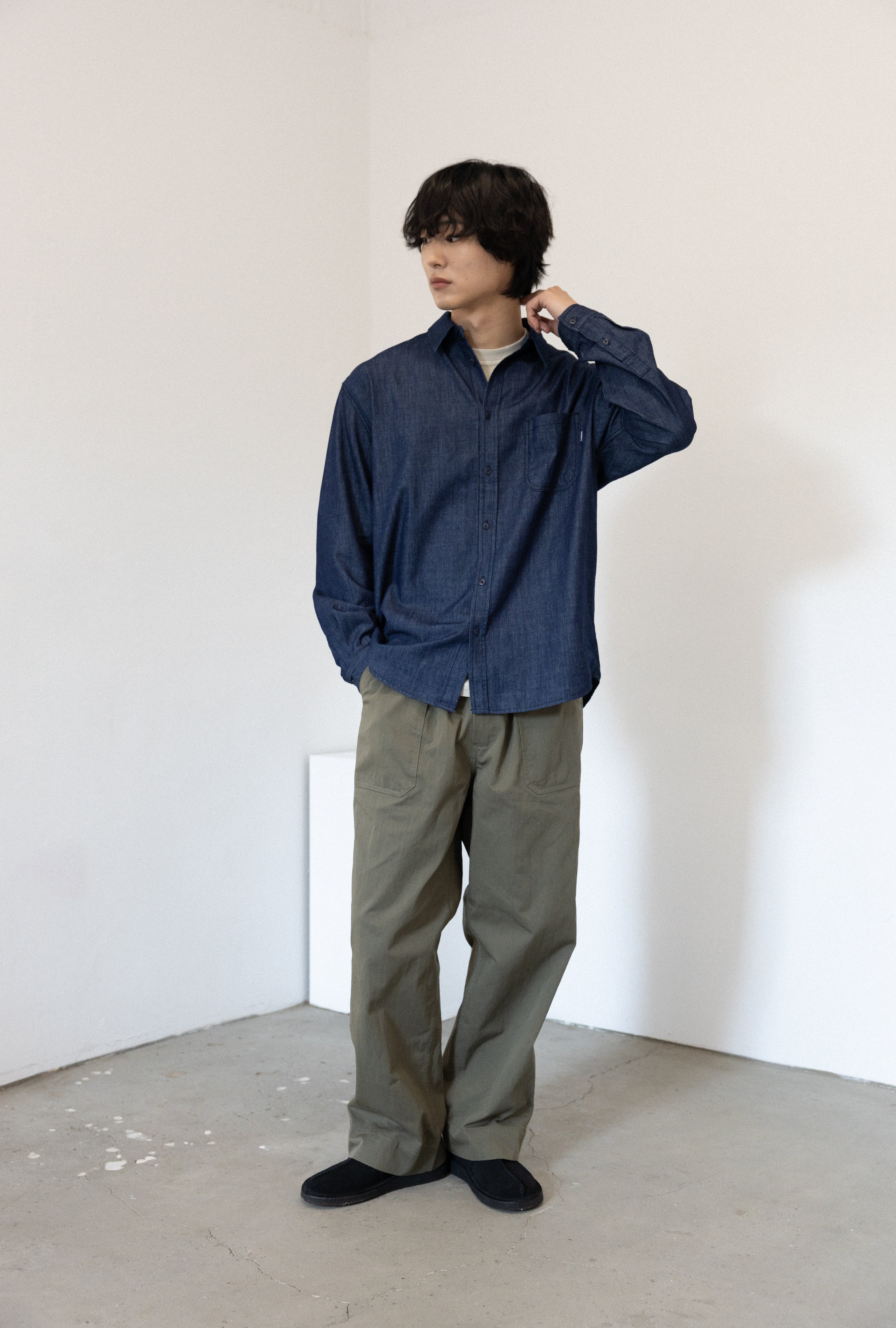 Person wearing a blue shirt and Khaki Green pants in a minimalistic setting