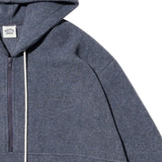 Close-up of a dark  gray zip-up hoodie with a white drawstring and a small embroidered logo on the chest, set against a plain white background.
