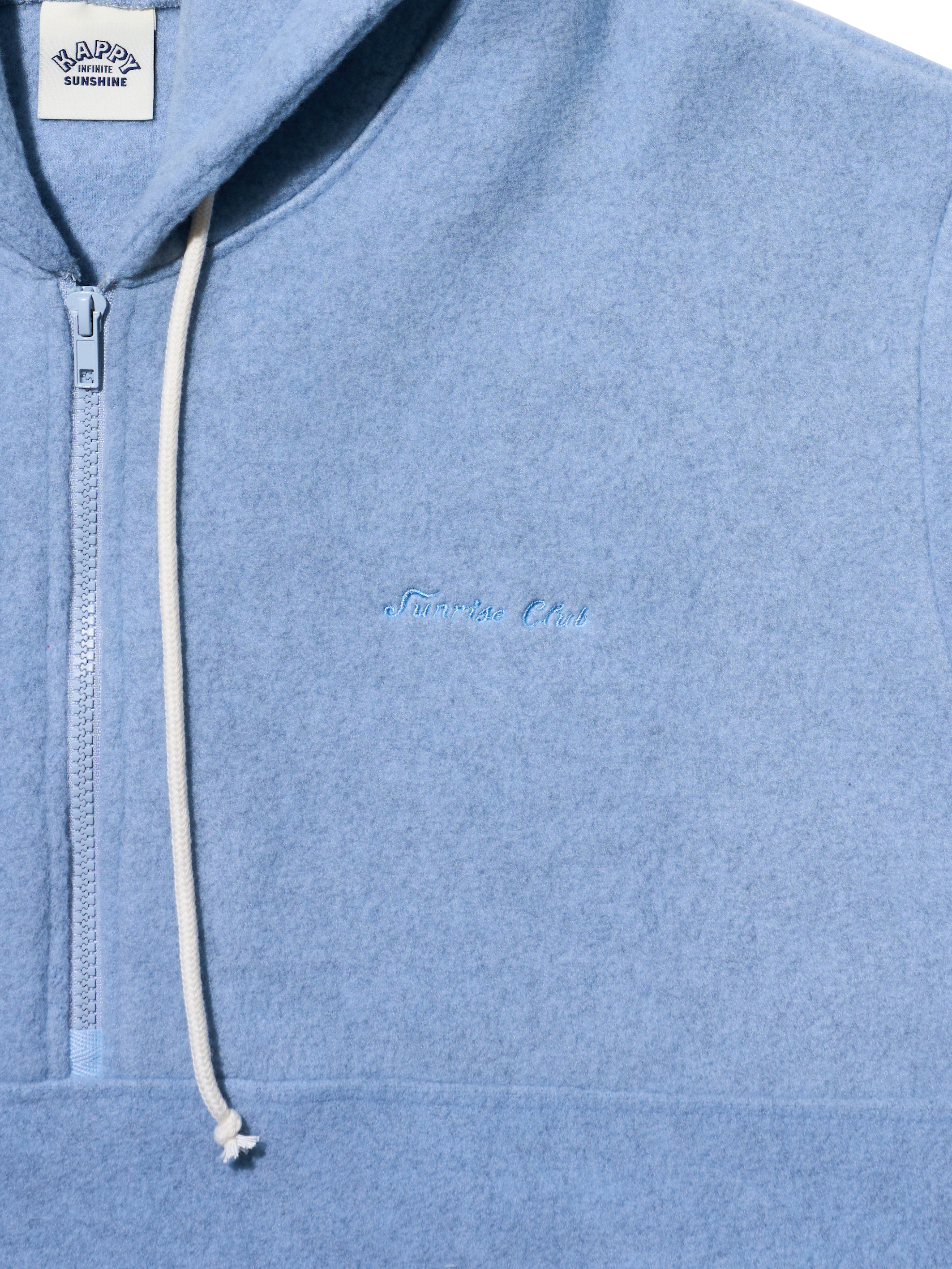 Close-up of a light blue heathered quarter-zip hoodie with a white drawstring and subtle tonal embroidery on the chest. A white brand label is visible at the collar.