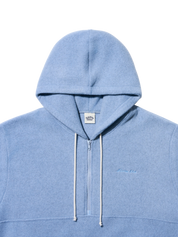 A light blue half-zip hoodie with white drawstrings and a small embroidered logo on the left chest, shown against a plain white background.