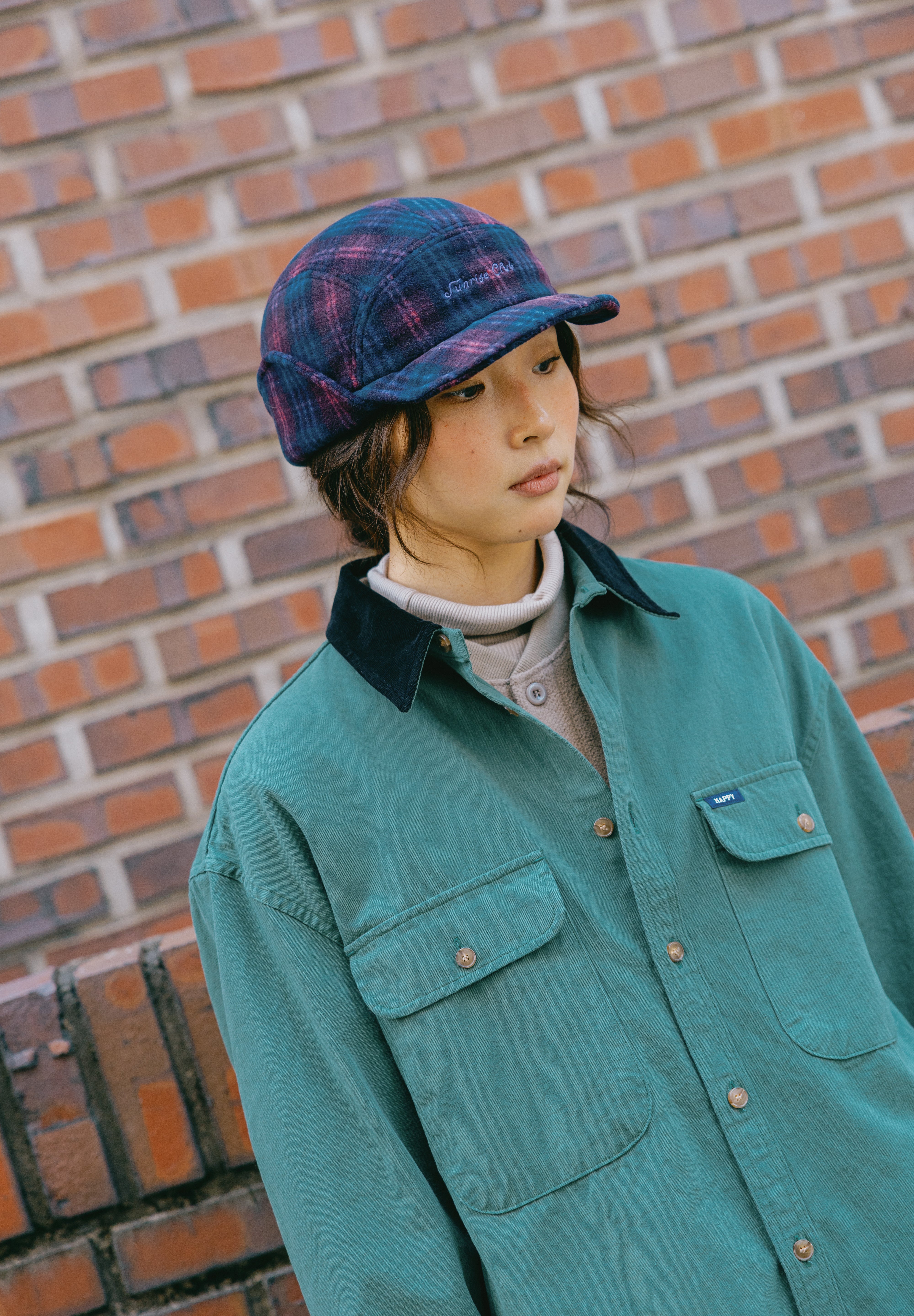 ear flaps in a dark blue and purple pattern, featuring white embroidered text on the front that reads 'Sunrise Club'.