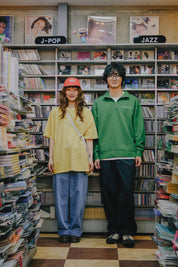 Two people standing in a store with bookshelves filled with music albums.