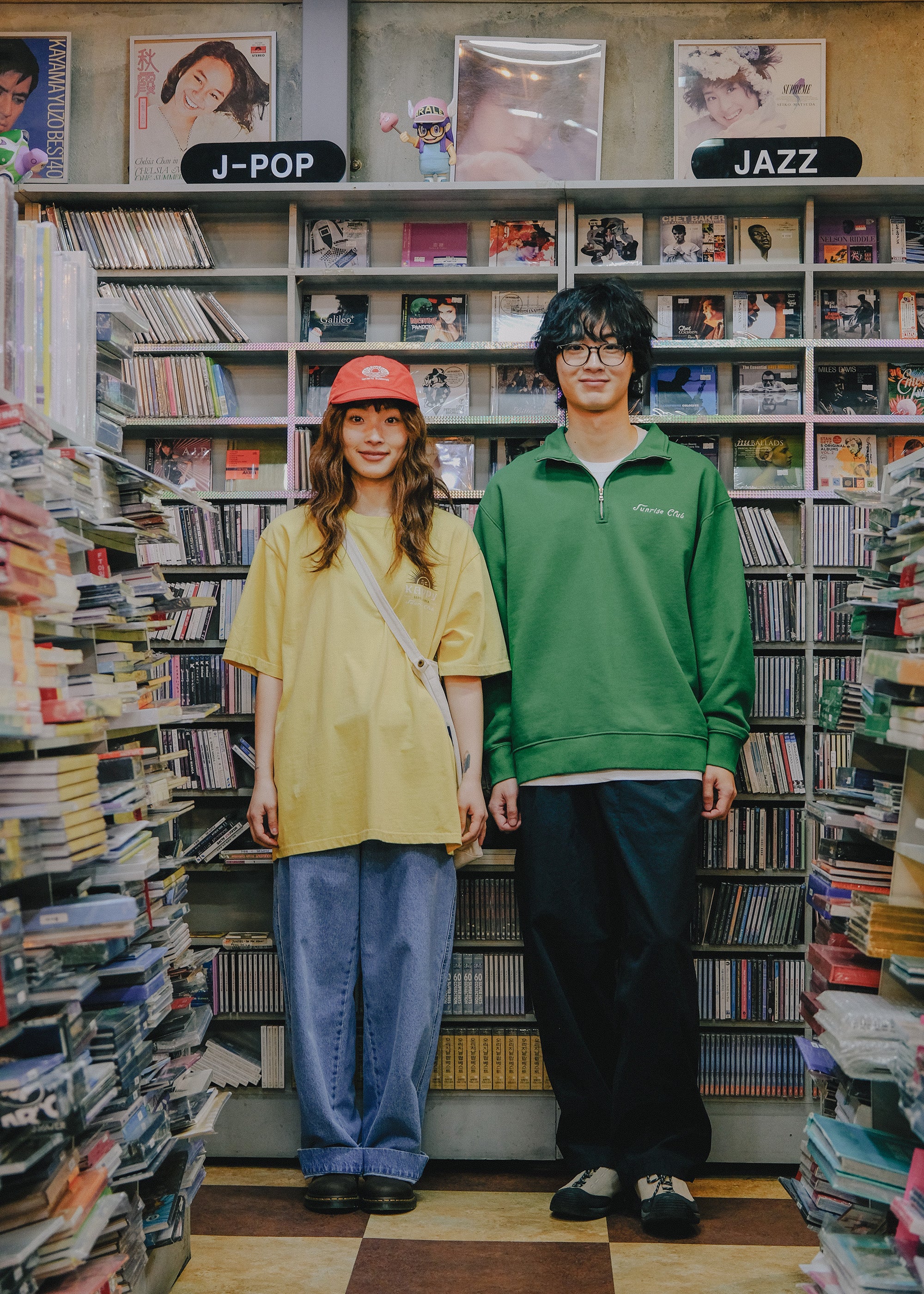 Two people standing in a store with bookshelves filled with music albums.