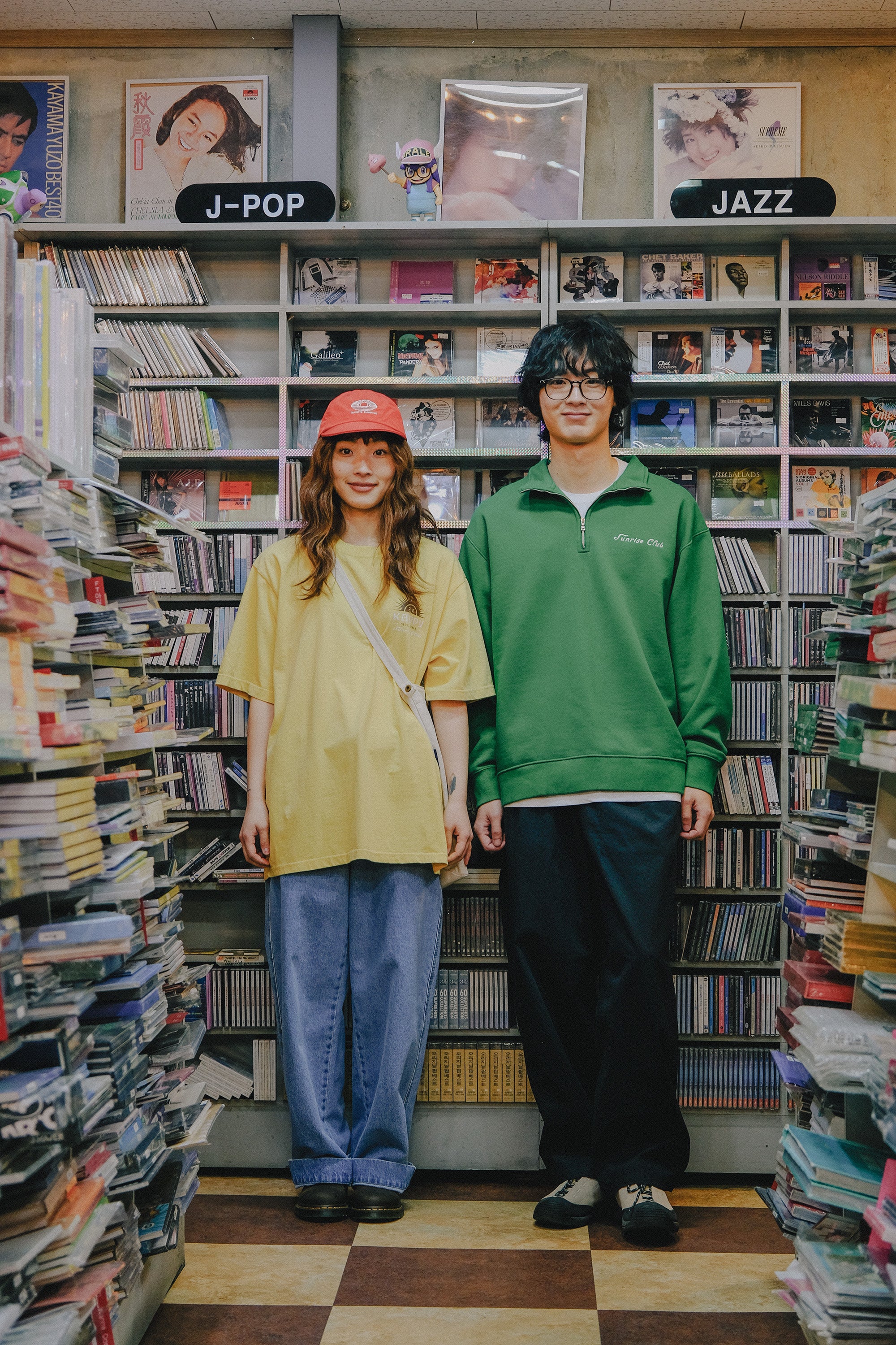Two people standing in a store with bookshelves filled with music albums.