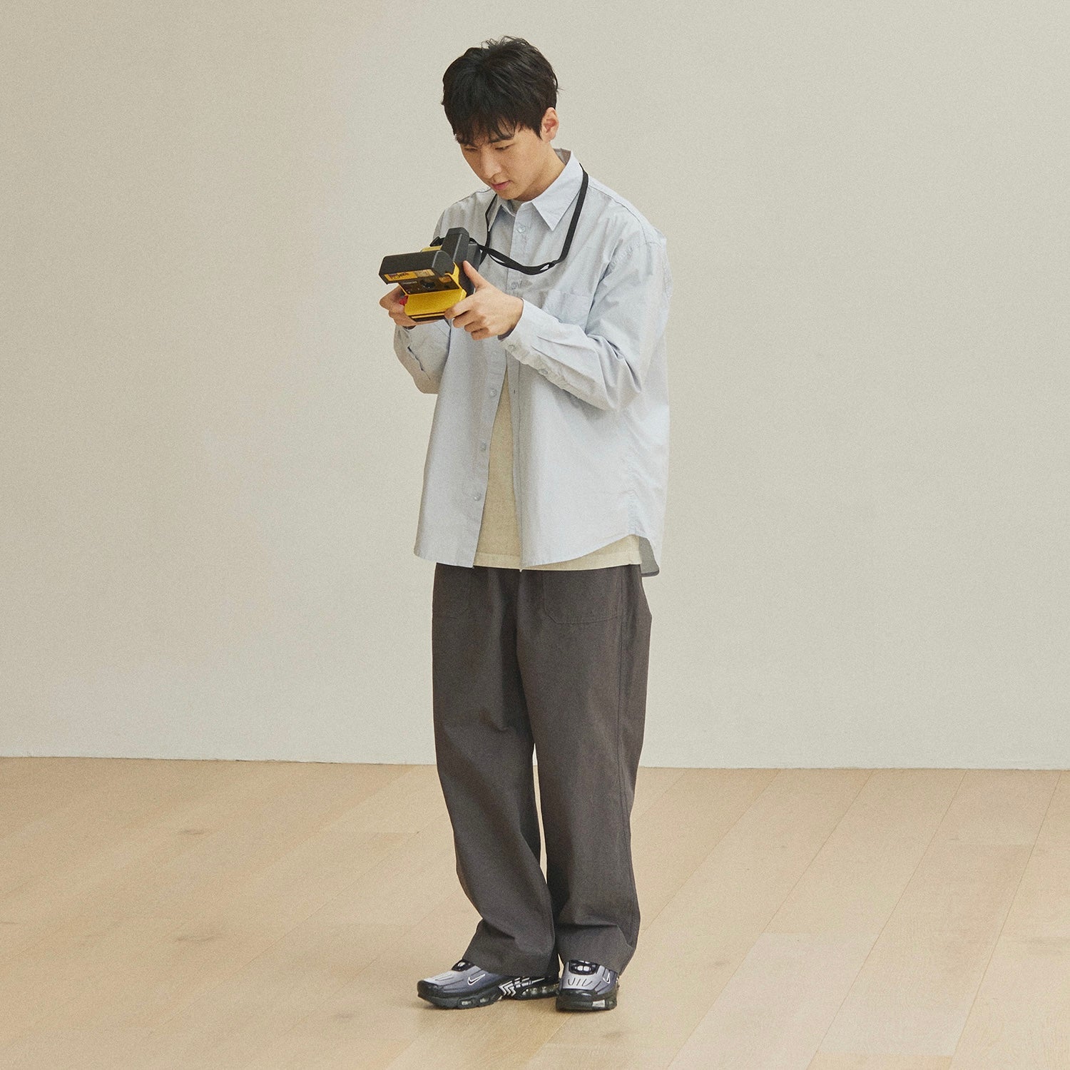 Person holding a camera against a plain background