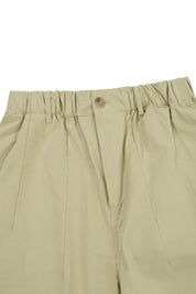 close up of elasticated waistband of Beige pants with a button on a white background