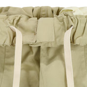 Close-up of beige fabric waistband with drawstrings on a white background