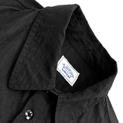 close up of a black shirt collar with a visible brand label on a white background