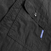 Close-up of a black shirt with infinite sunshine label on the chest pocket.