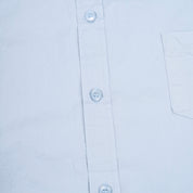 Close-up of a light blue shirt with buttons and a pocket on a white background