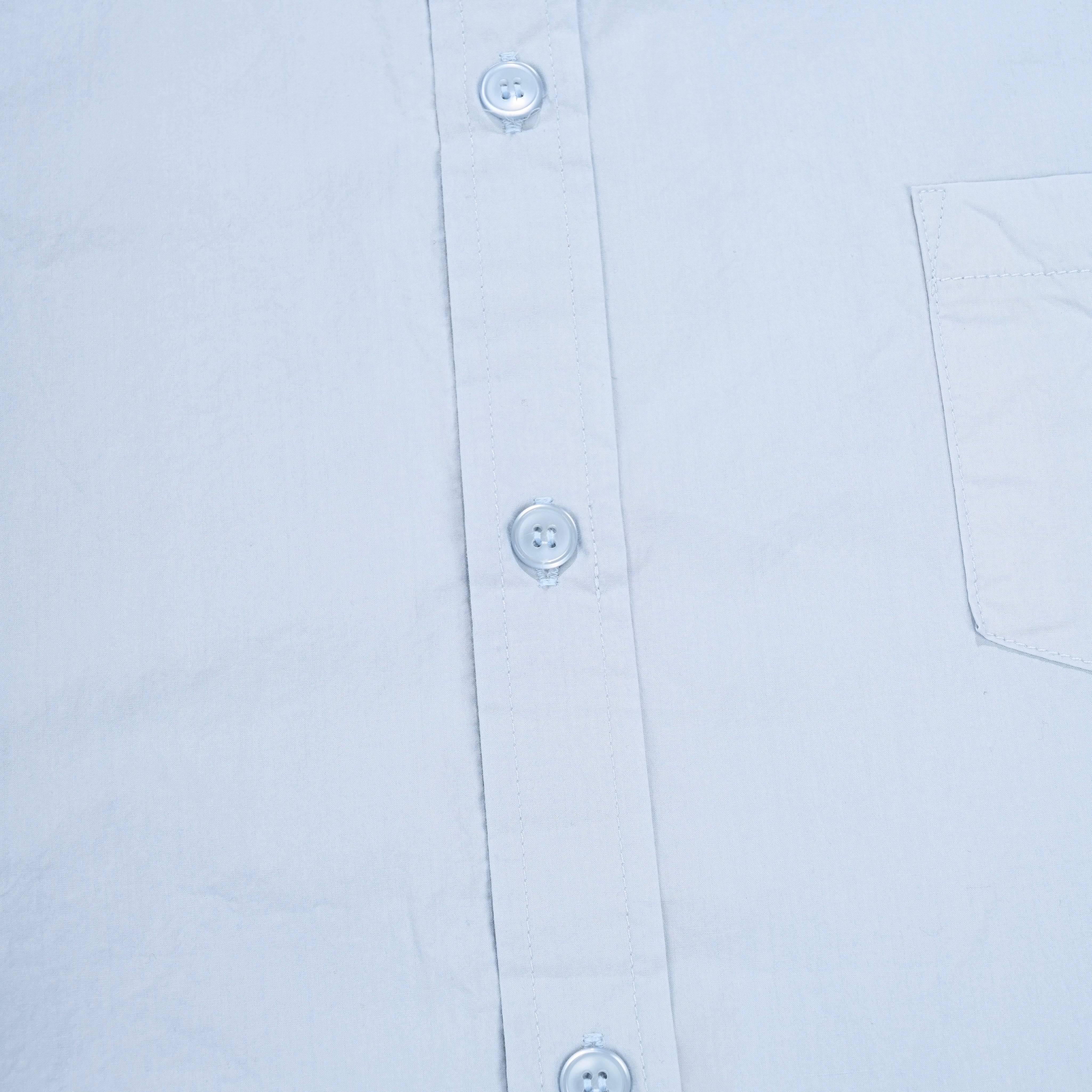 Close-up of a light blue shirt with buttons and a pocket on a white background