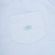 Close-up of a light blue pocket on a shirt with a logo.