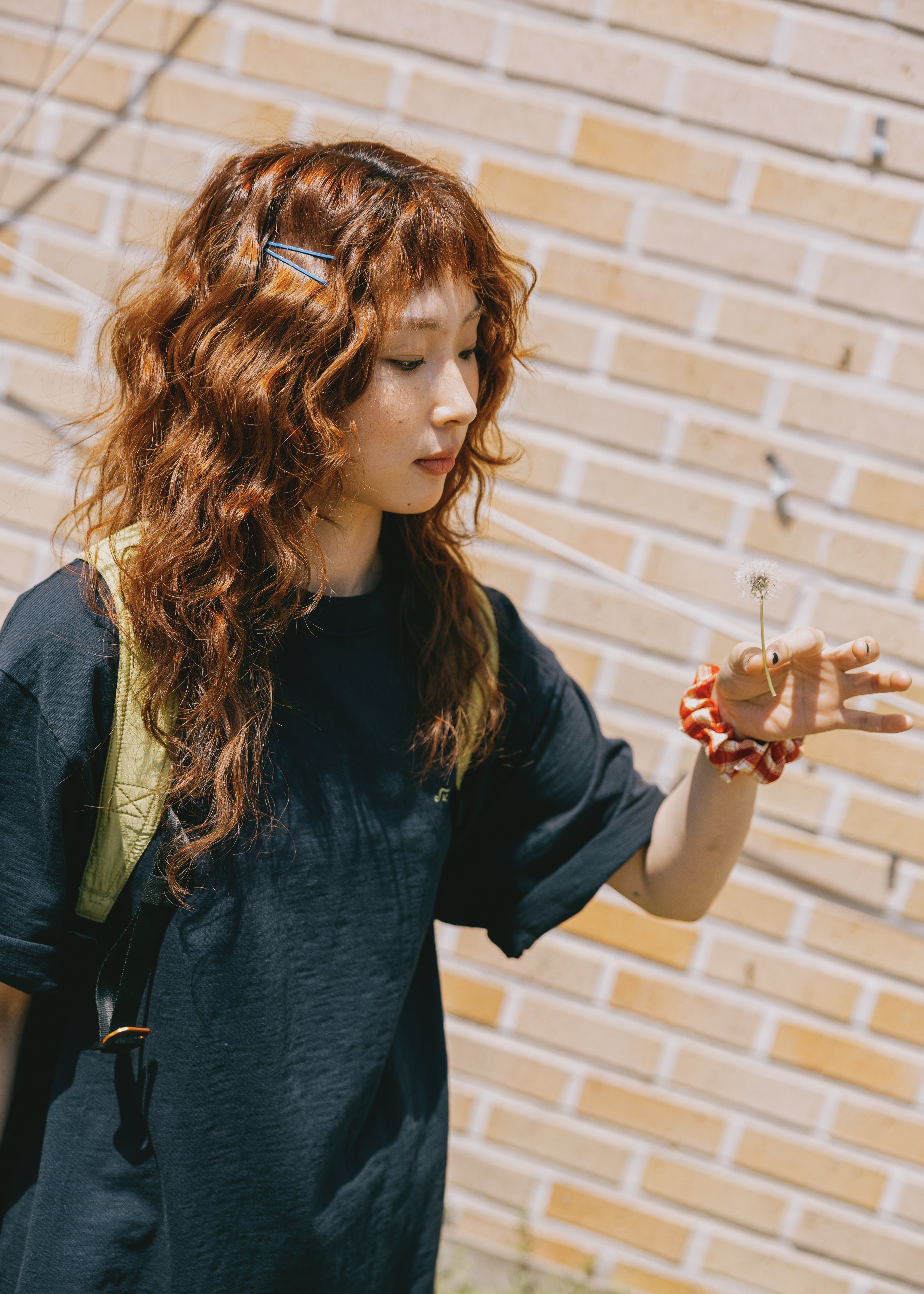 Woman with long wavy hair standing against a brick wall