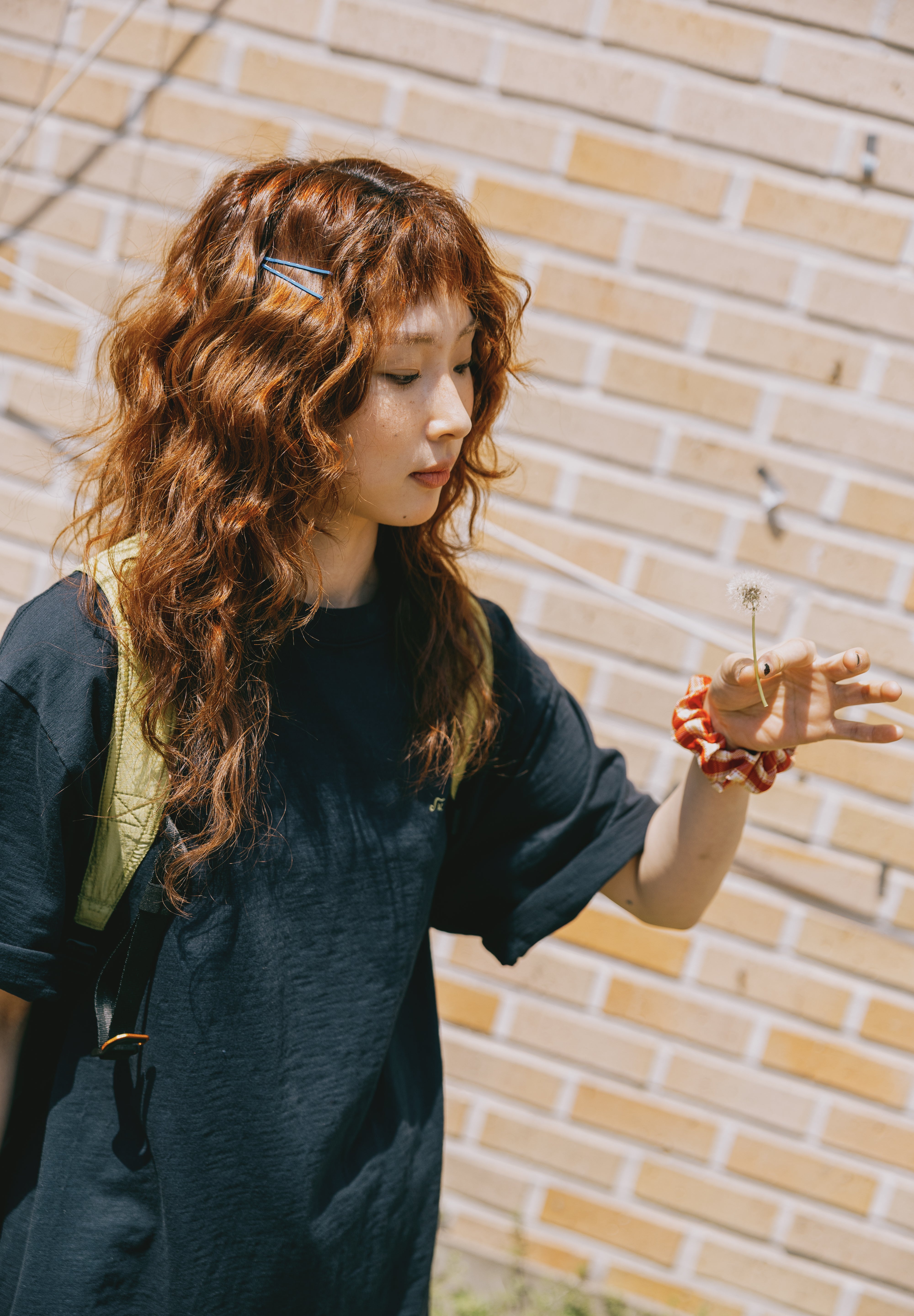 Woman with long wavy hair standing against a brick wall