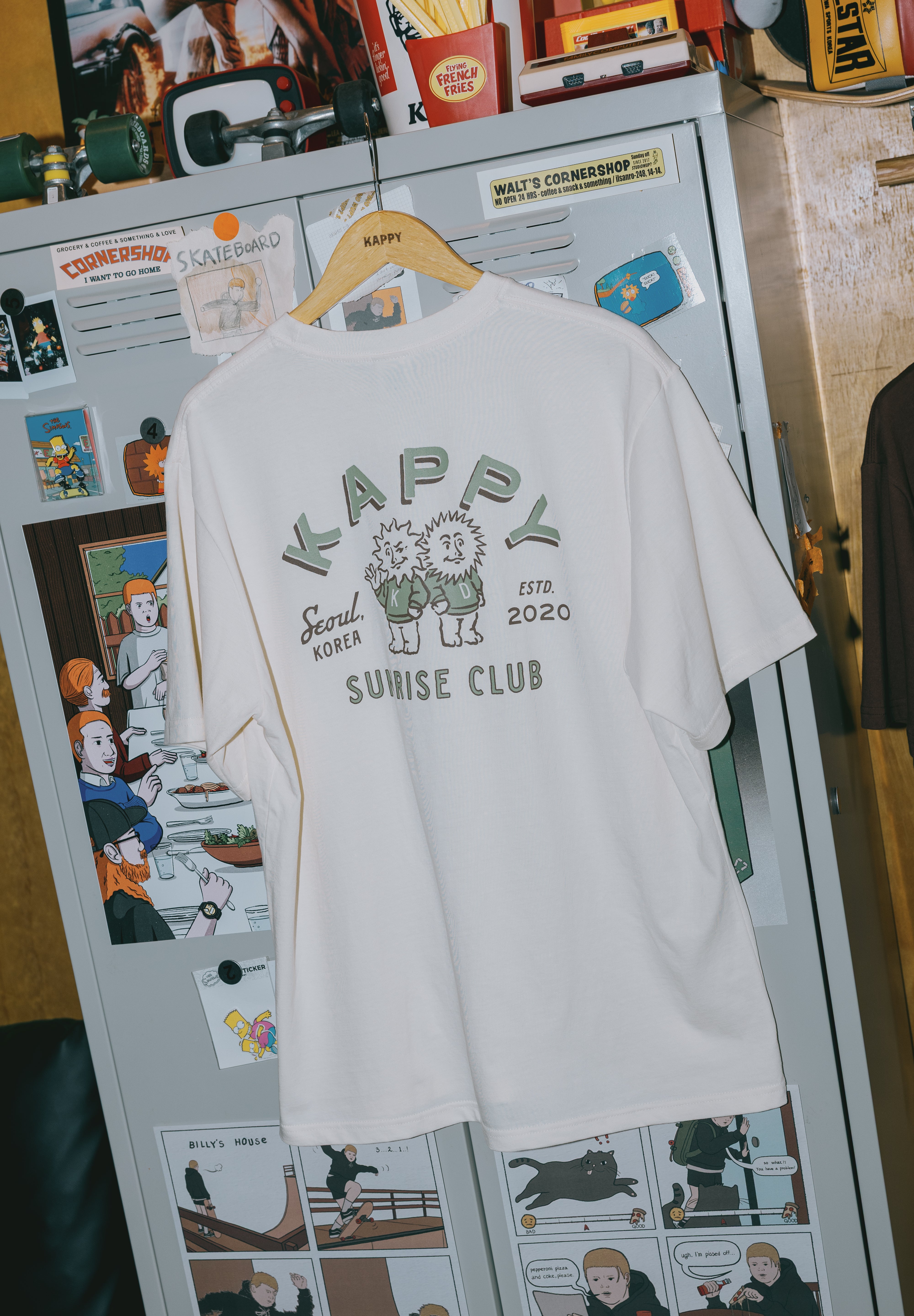 cream t-shirt with graphic design on a refrigerator with magnets and photos.