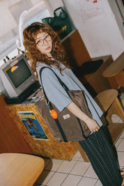 Person wearing a brown bag with a visible brand logo in an indoor setting.
