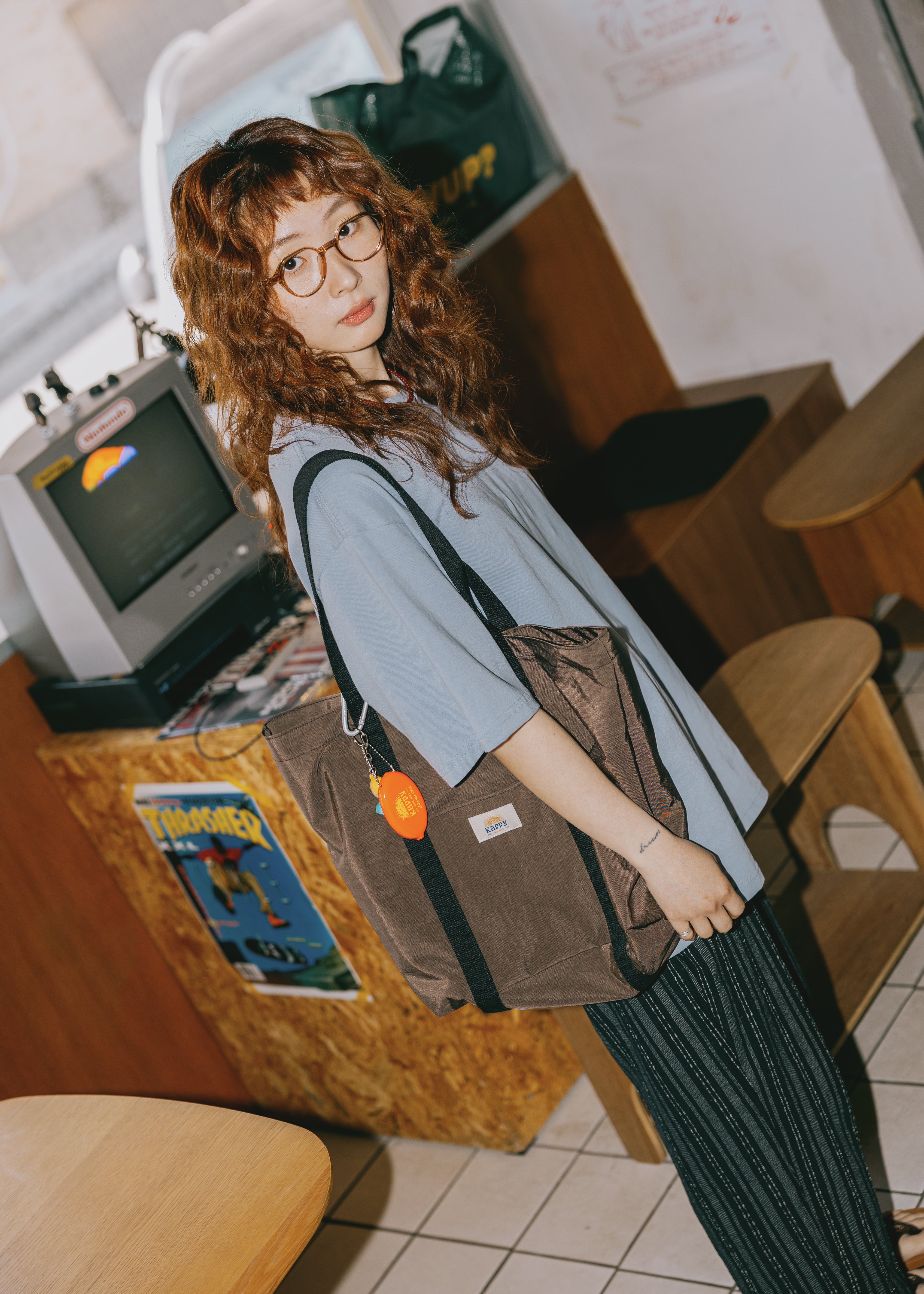 Person wearing a brown bag with a visible brand logo in an indoor setting.