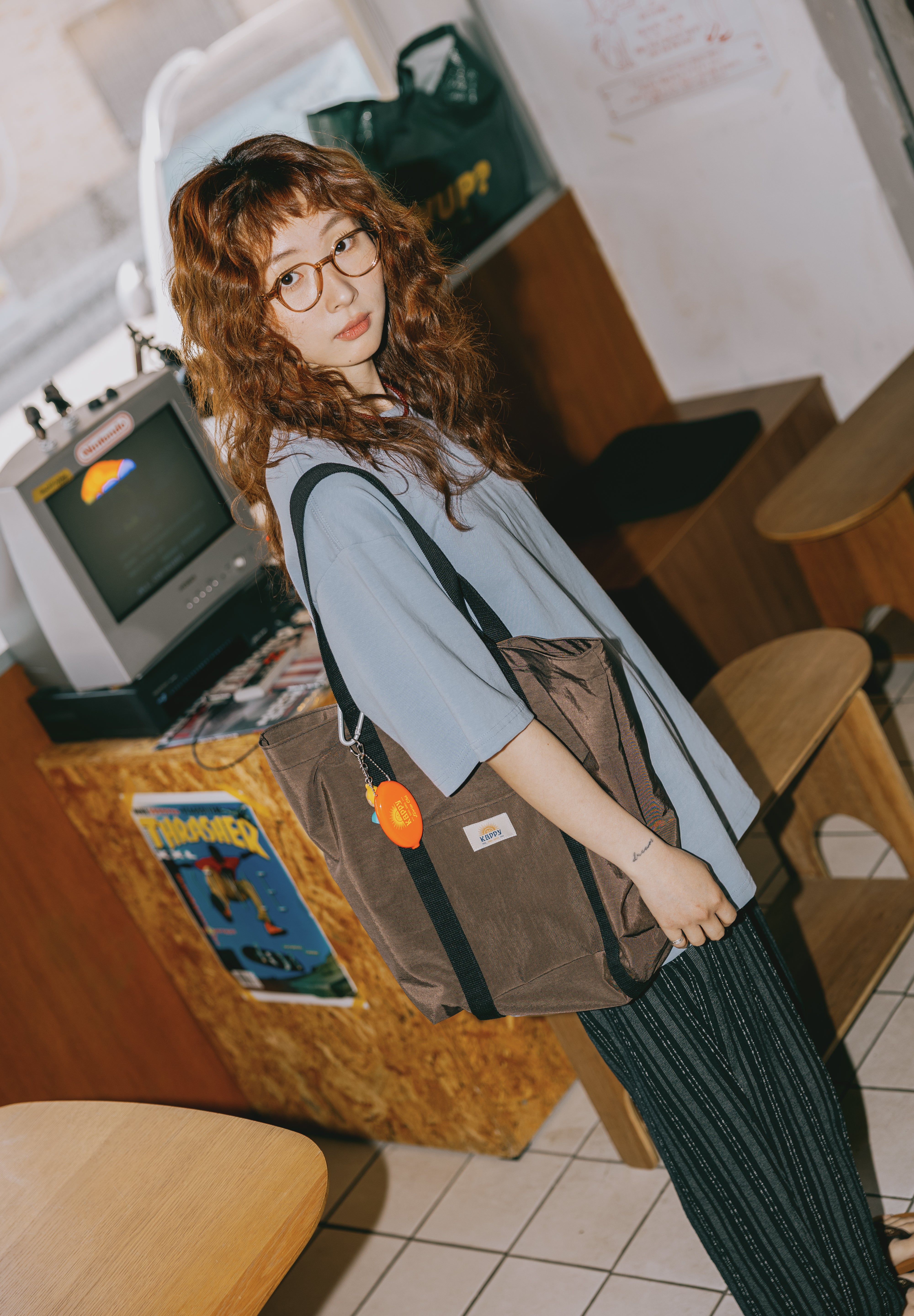 Person wearing a brown bag with a visible brand logo in an indoor setting.