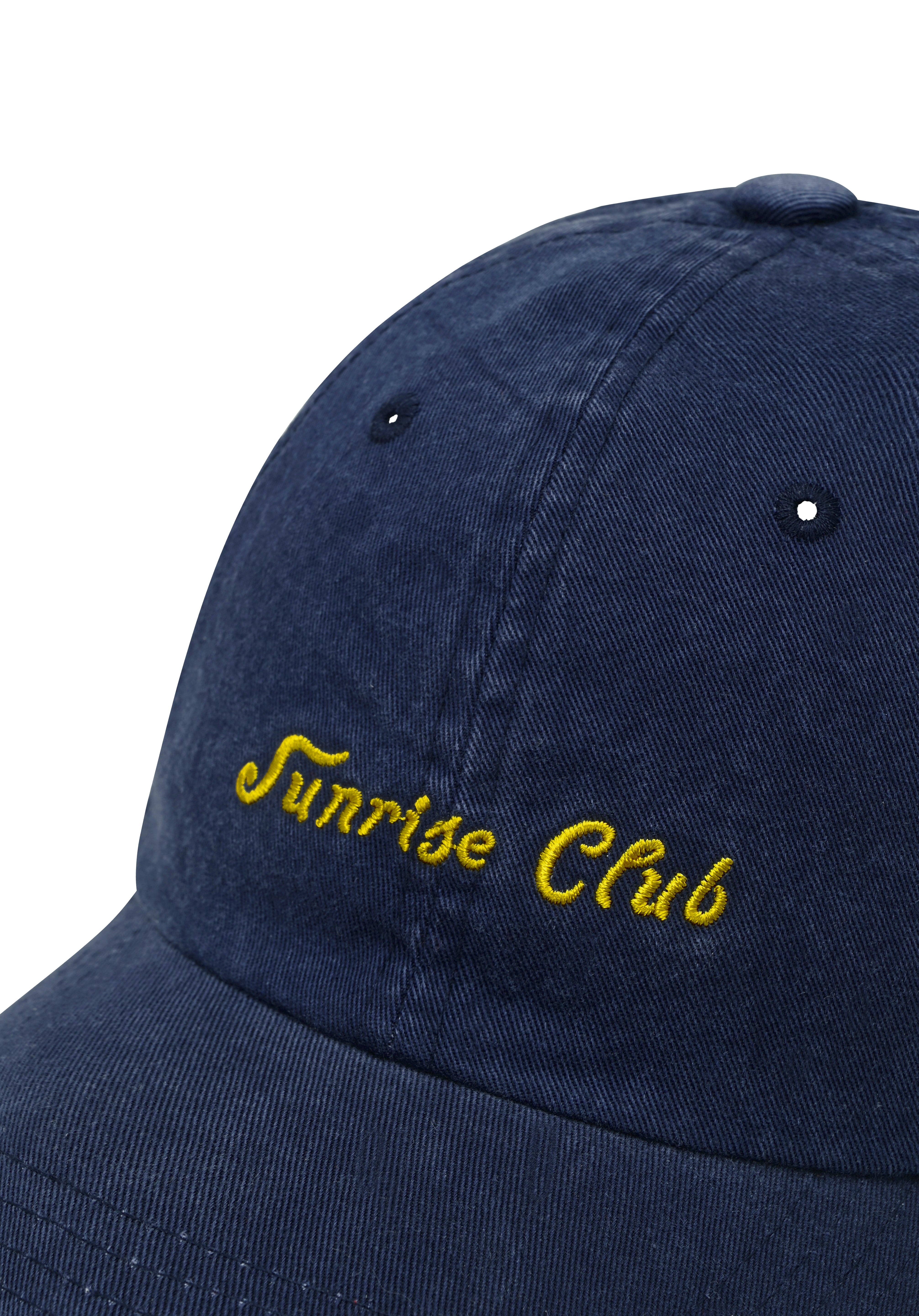 Close up of Navy blue cap with 'Sunrise Club' embroidered in yellow on a white background