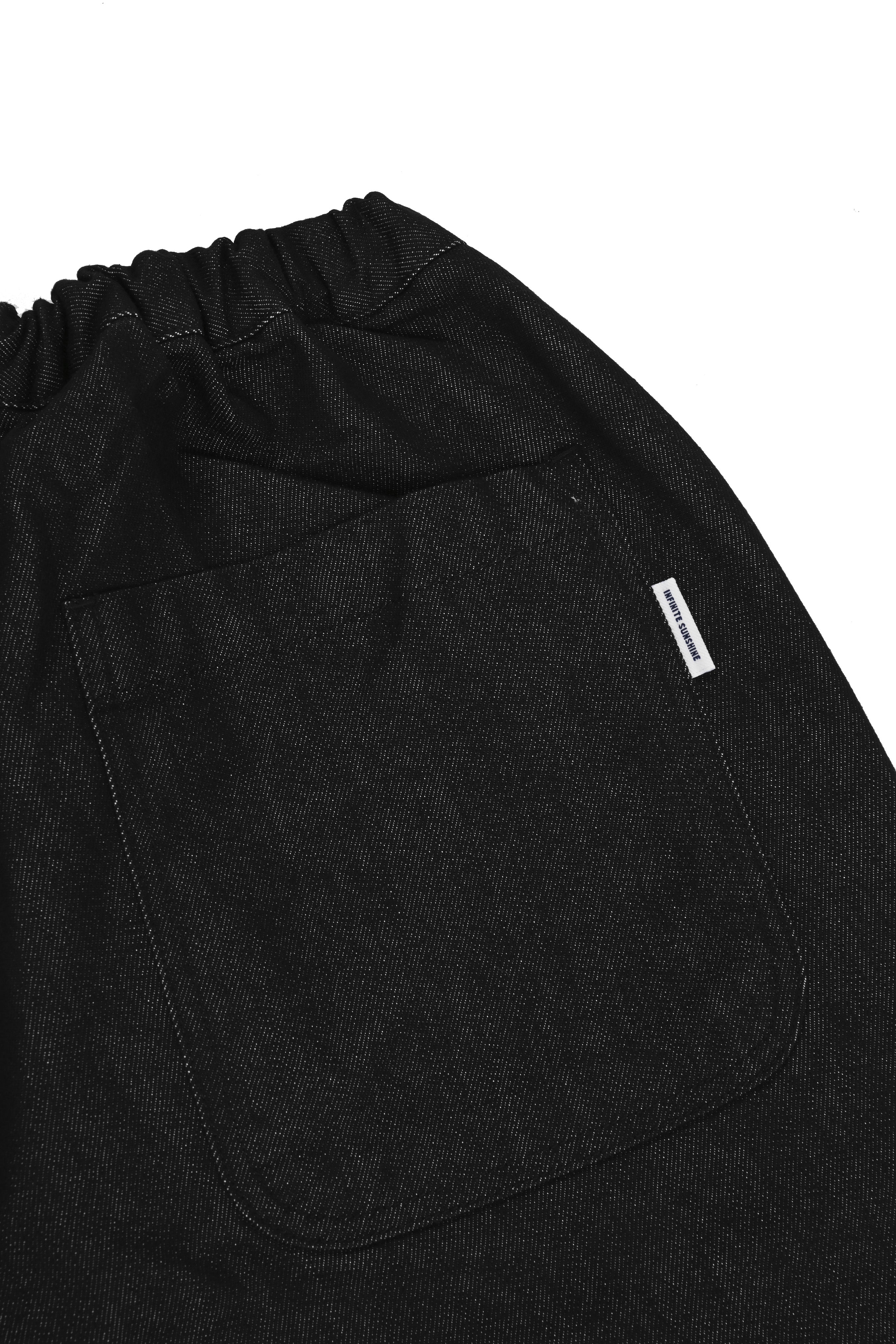 close up of rear pocket and waistband of black denim pants with white label
