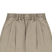Close-up of beige pleated pants with an elastic waistband on a white background
