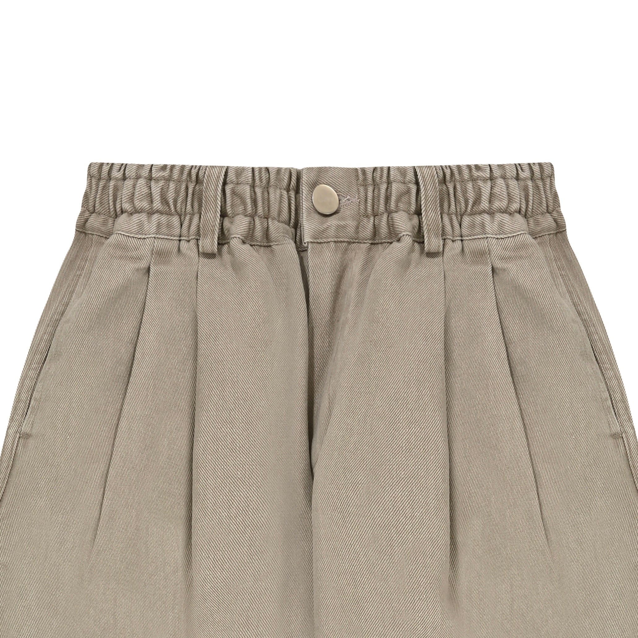 Close-up of beige pleated pants with an elastic waistband on a white background
