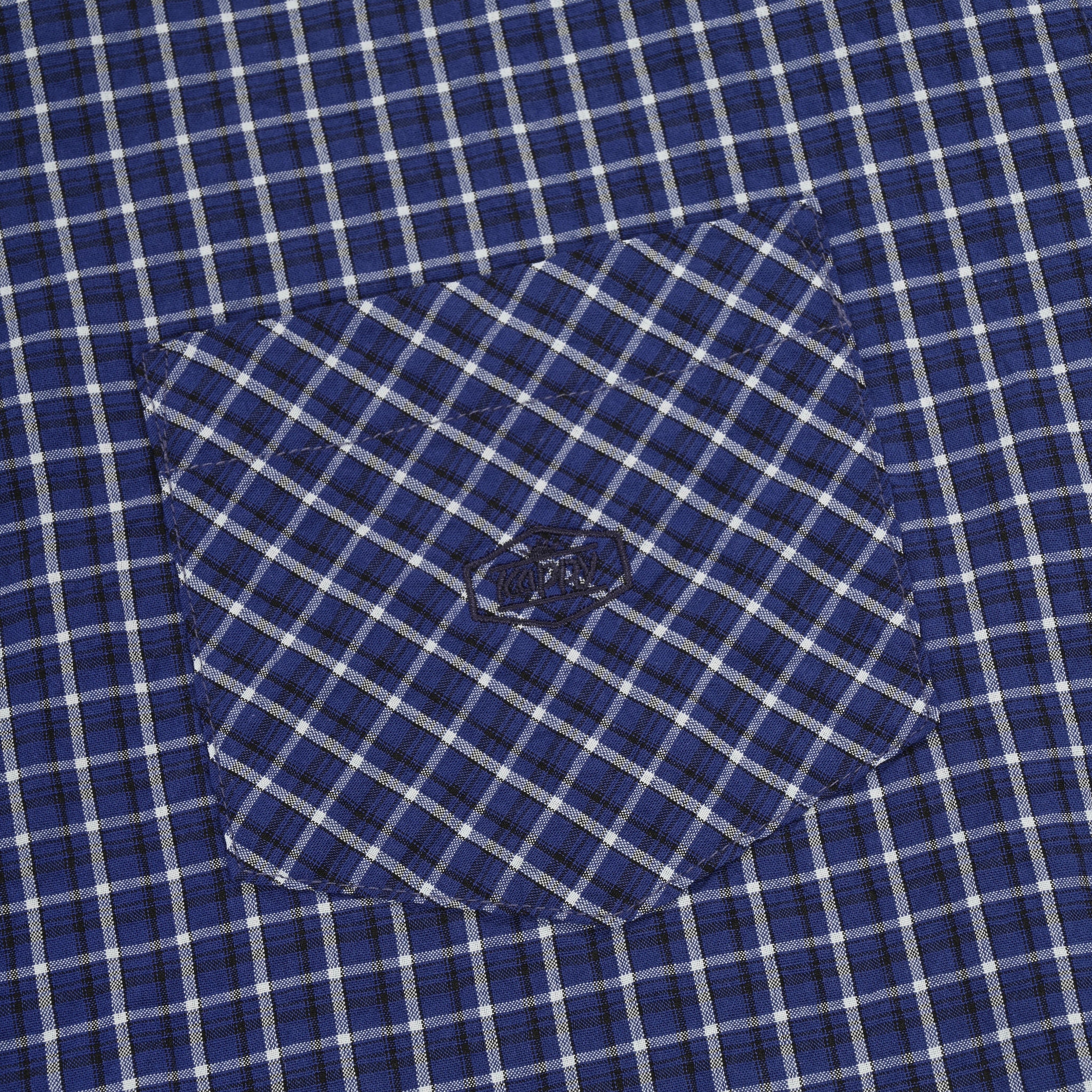 Close-up of pocket on a blue and white checkered shirt with a button.
