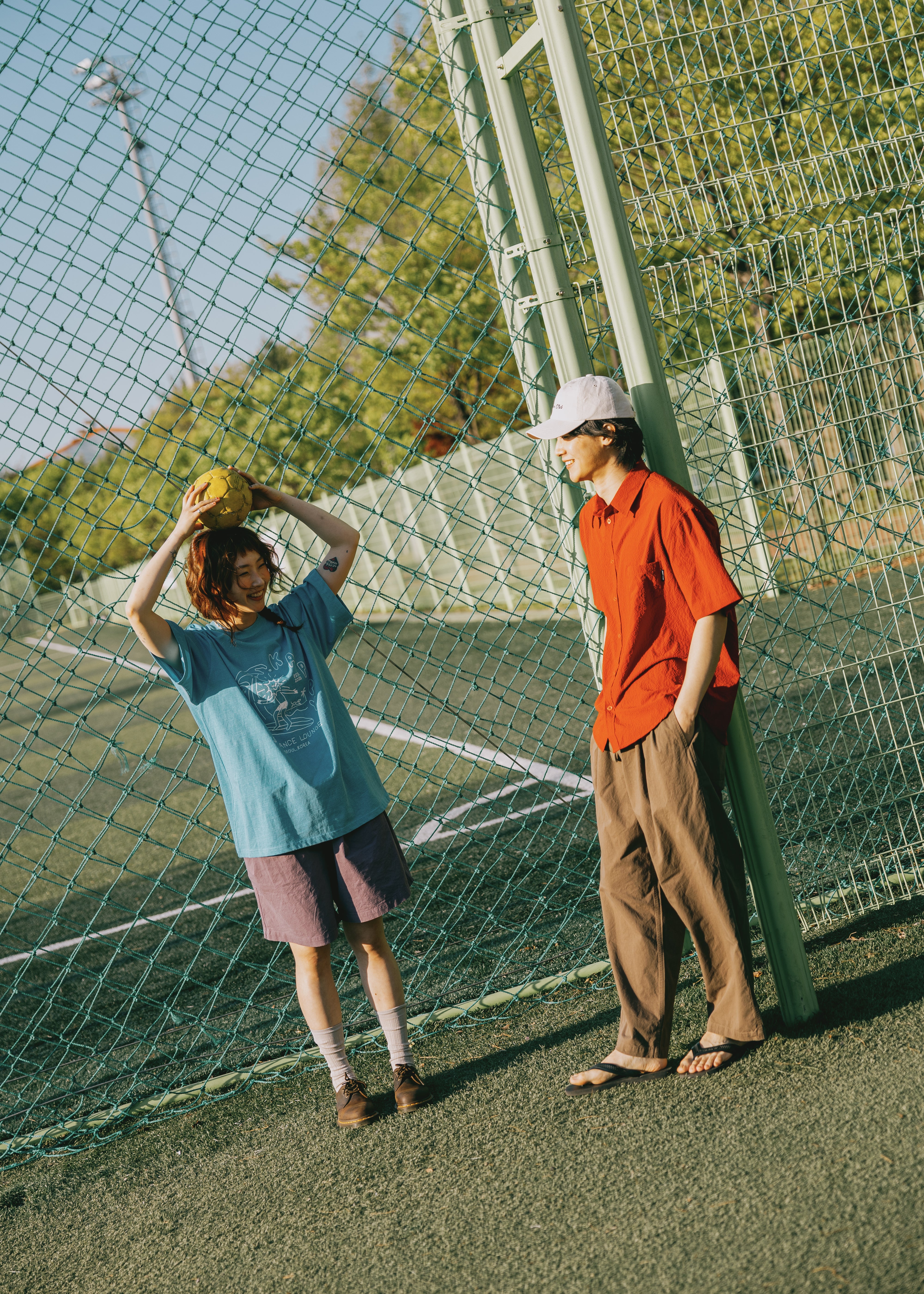 Two people on a tennis court with a net in the background