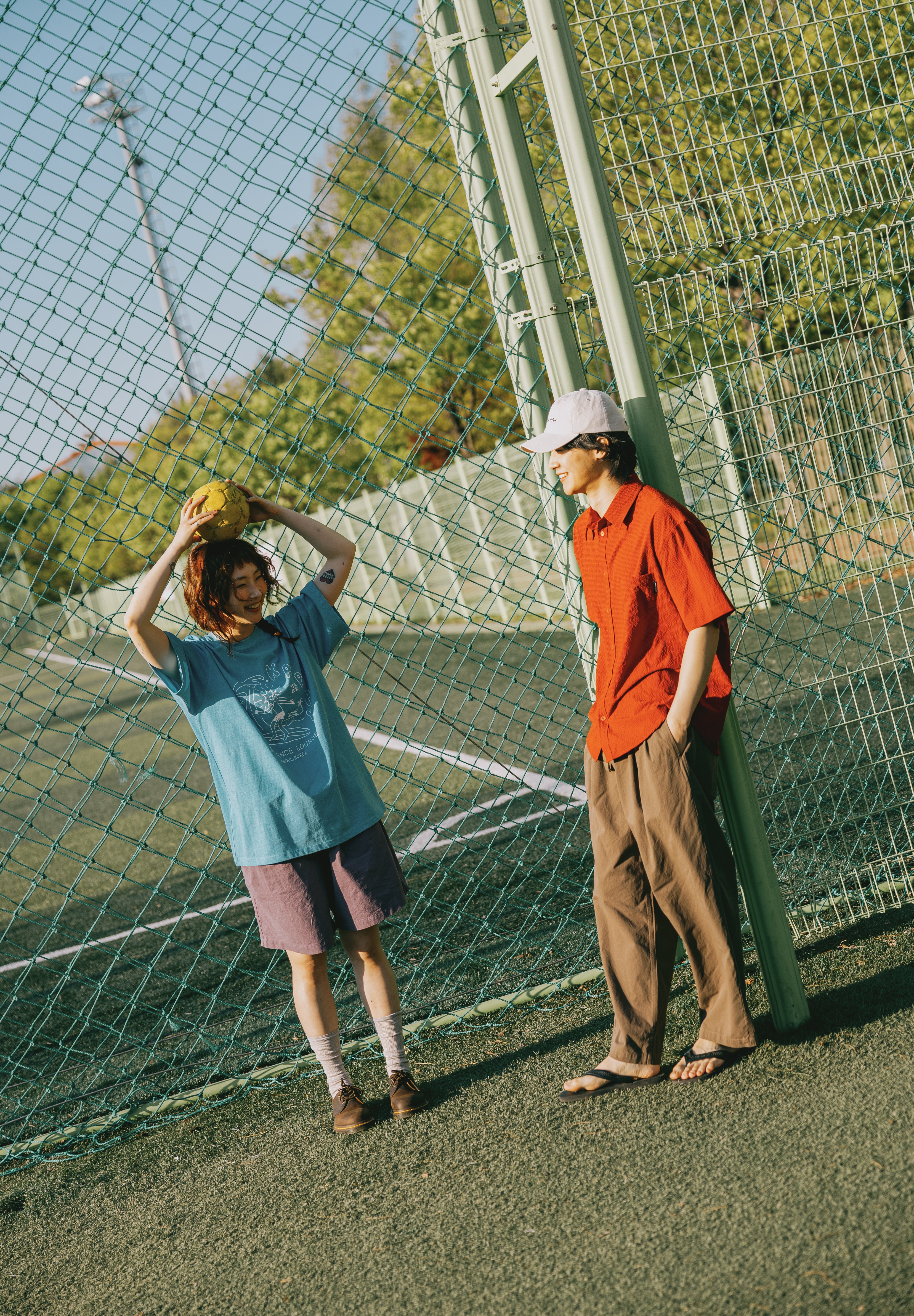 Two people on a tennis court with a net in the background