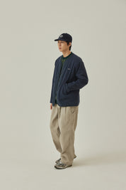 Person wearing a navy jacket and beige pants on a plain background
