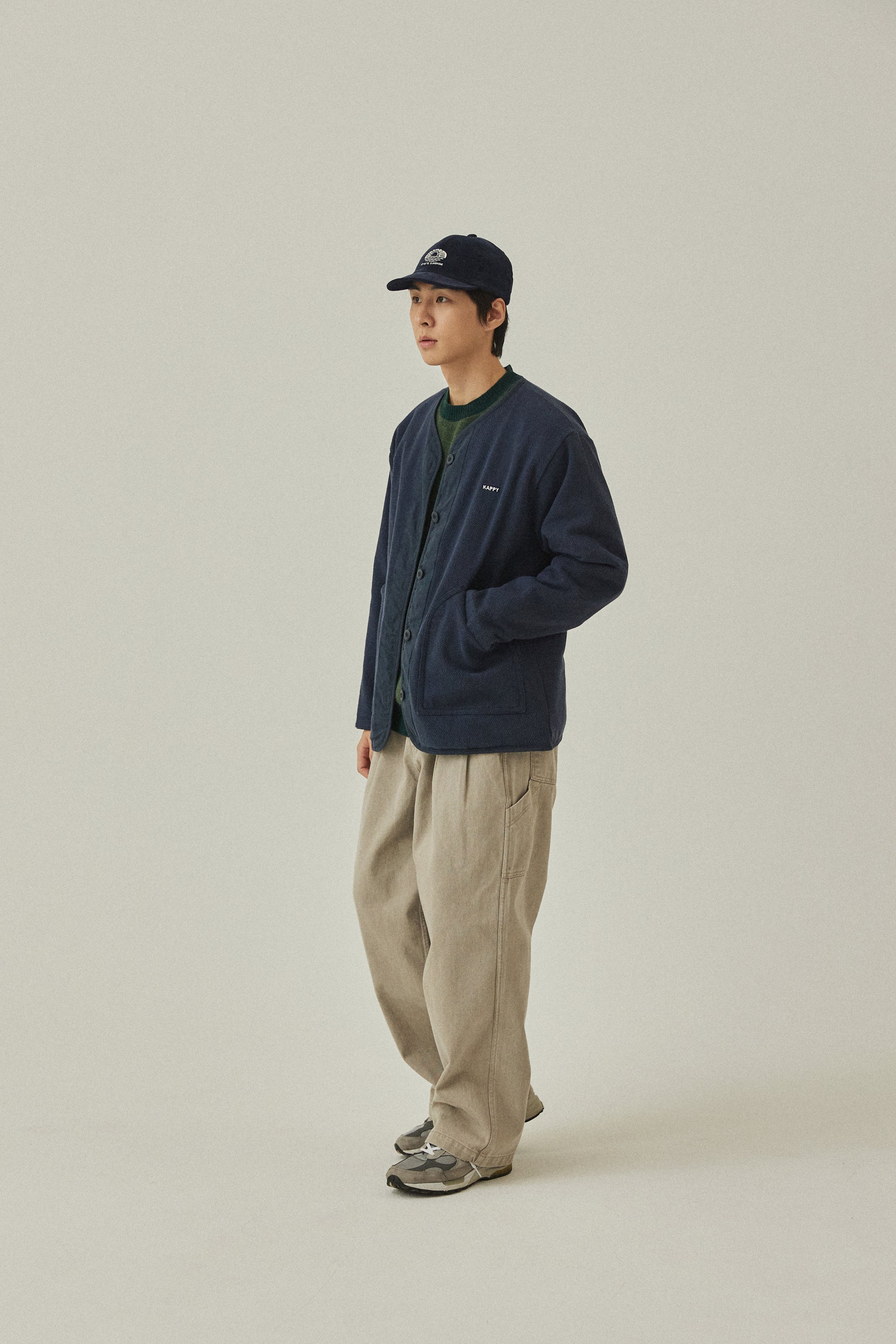 Person wearing a navy jacket and beige pants on a plain background