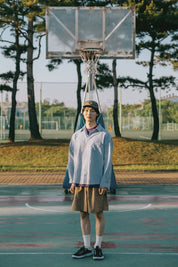 Person standing on a basketball court with a hoop in the background
