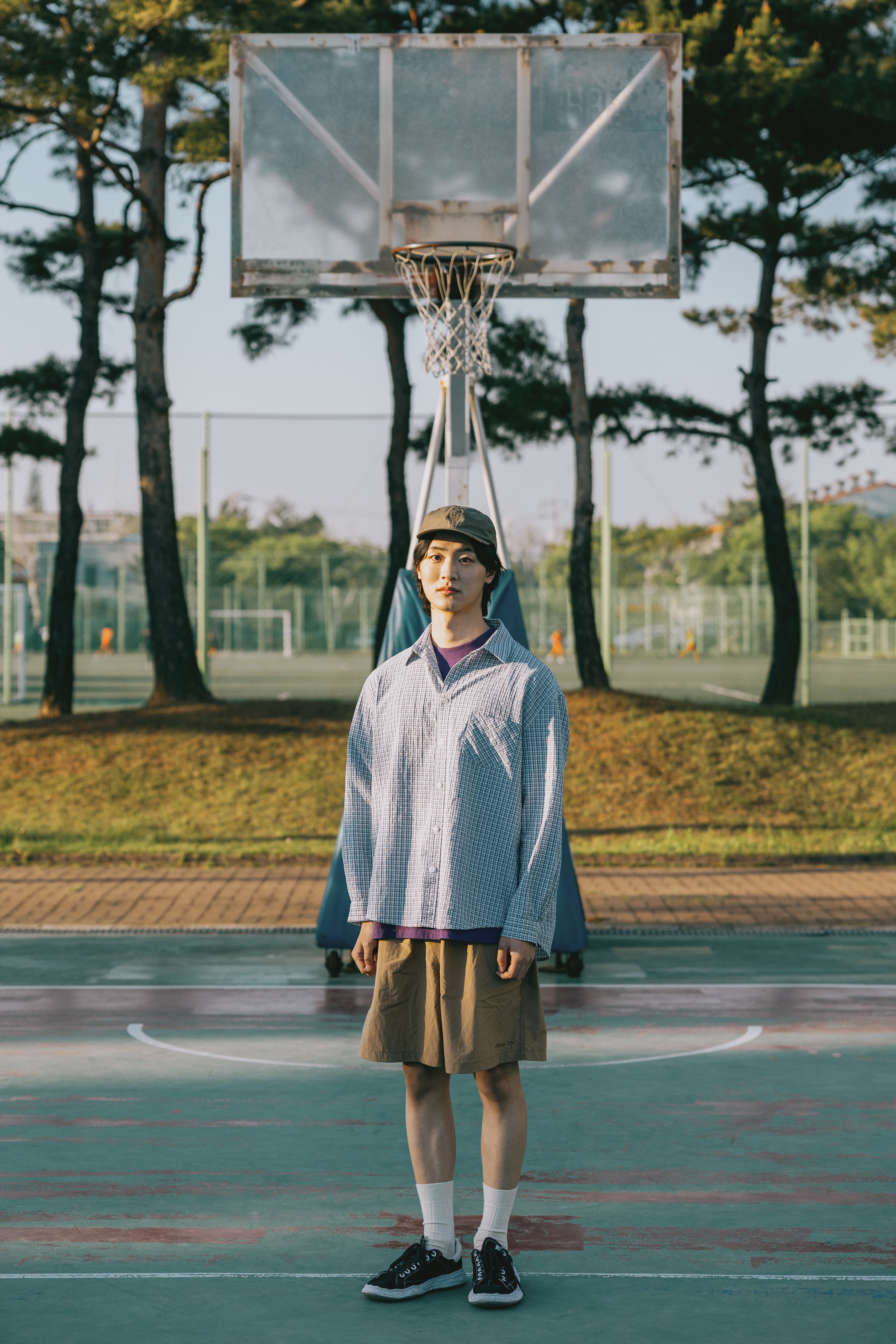 Person standing on a basketball court with a hoop in the background