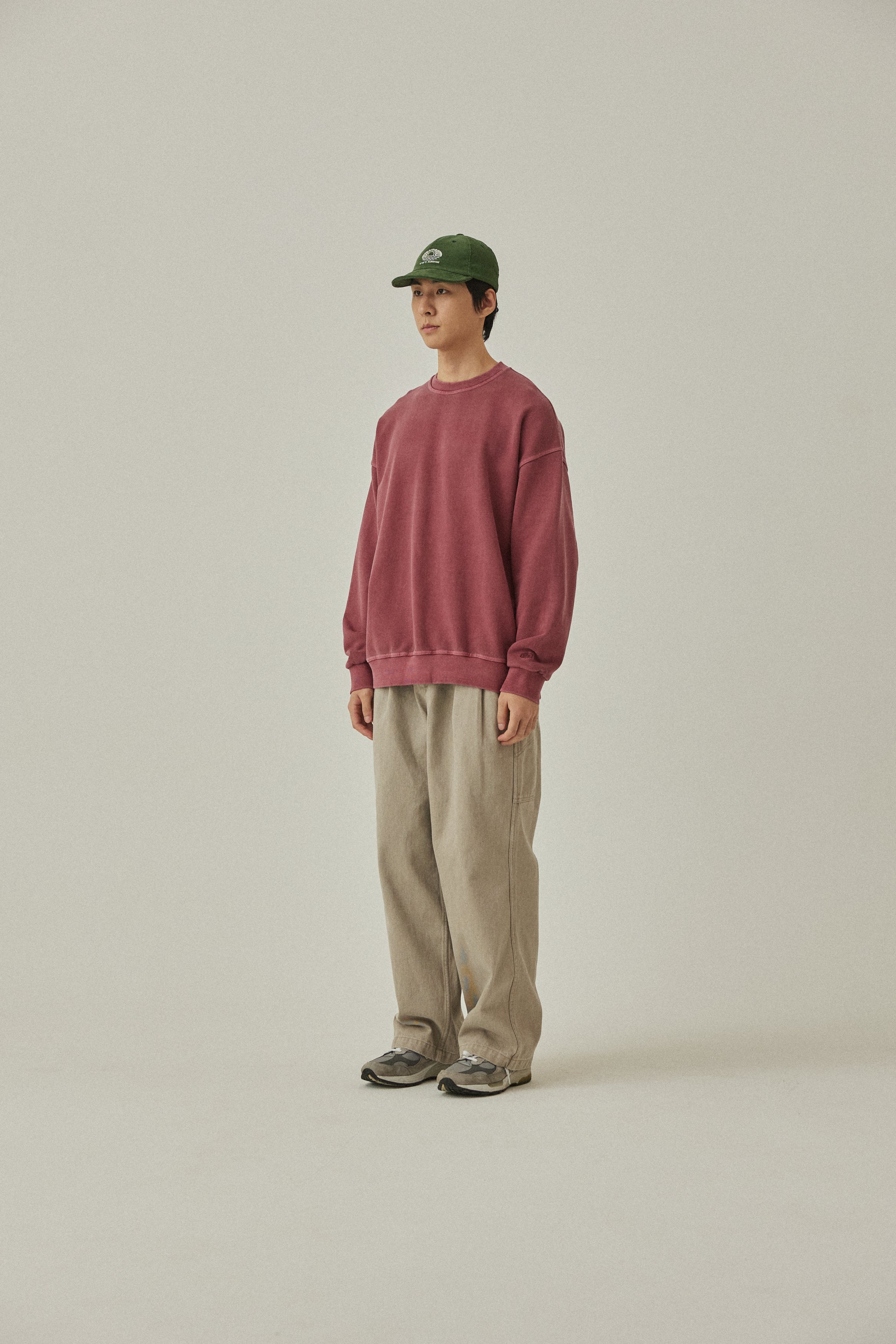 Person wearing a red sweatshirt and beige pants on a plain background