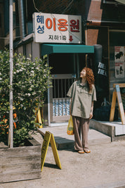 girl in Pigment Henley shirt standing on a street looking up to the sky