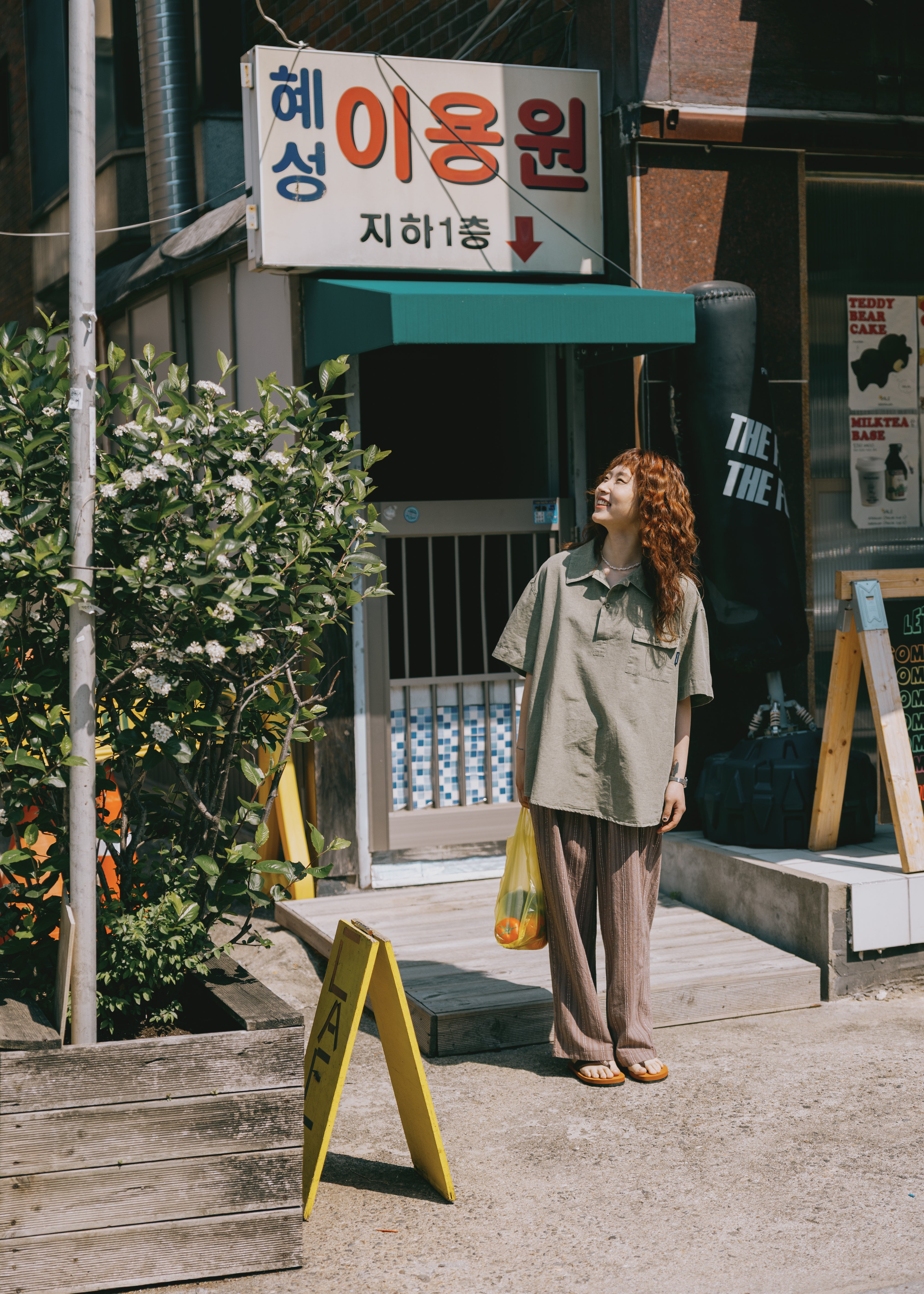 girl in Pigment Henley shirt standing on a street looking up to the sky
