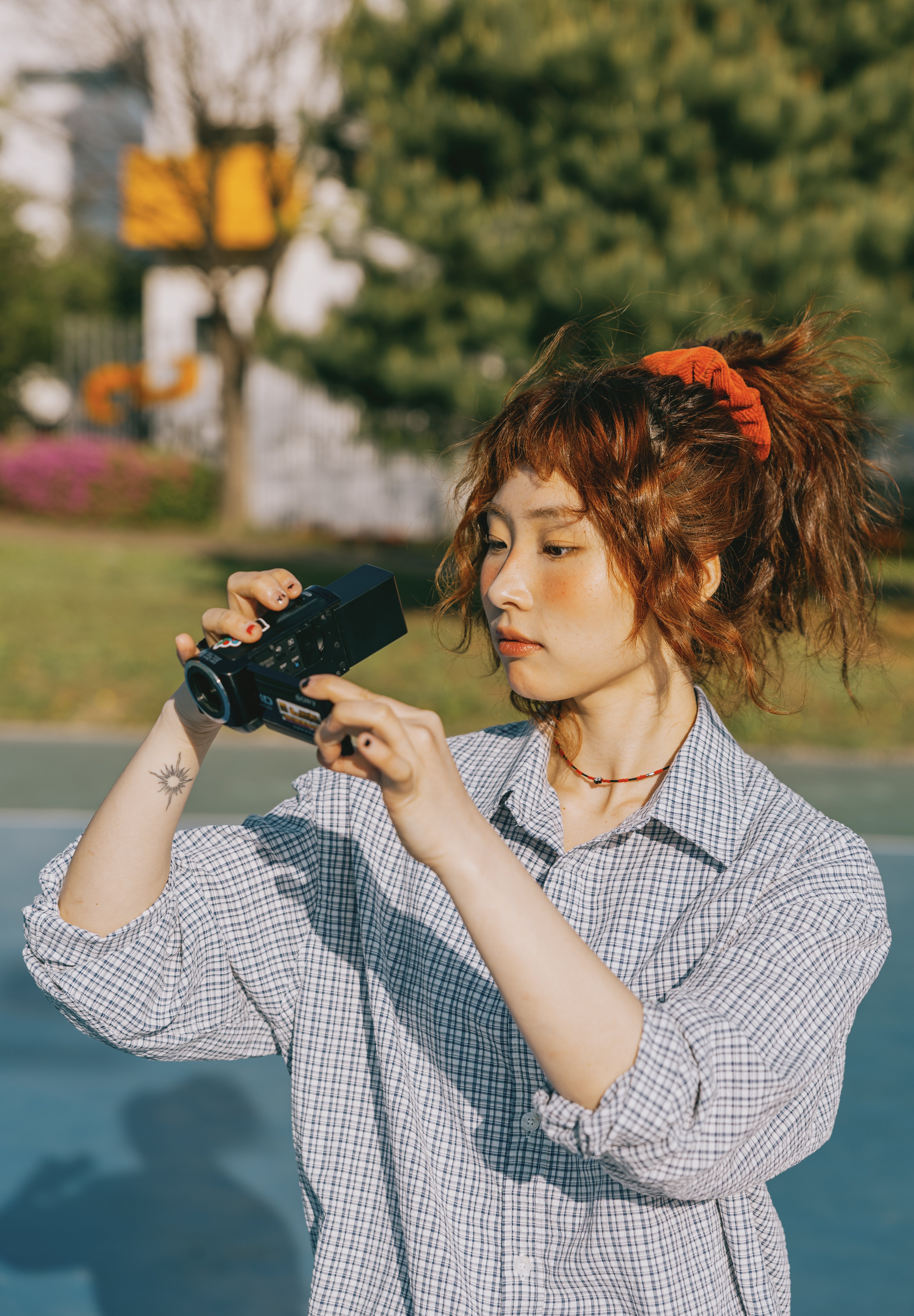 Person holding a camera outdoors with greenery in the background